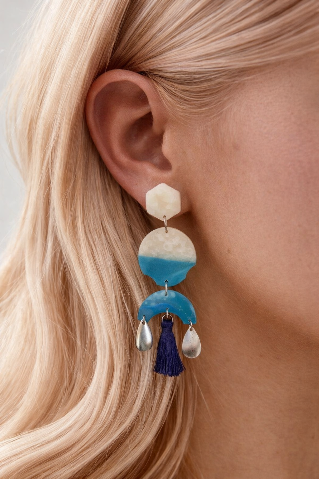 Ocean-toned geometric drop earrings with navy tassel and pearl drops — worn close-up