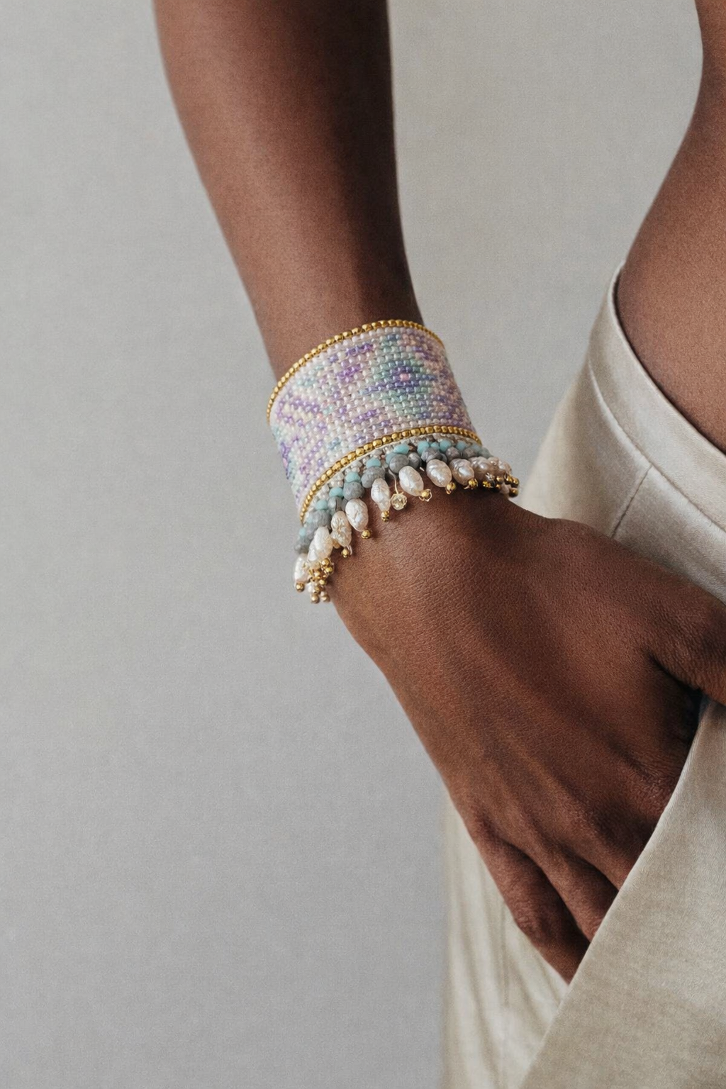Wide woven seed-bead cuff bracelet with pearl fringe — worn on wrist, lifestyle shot