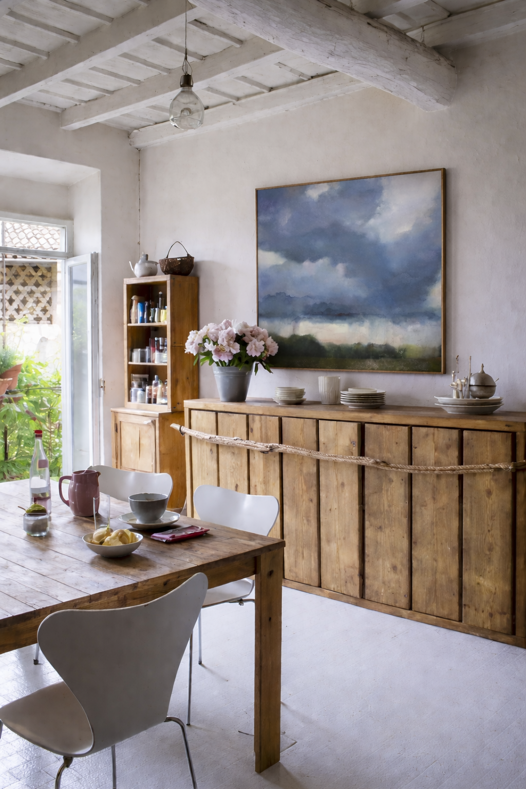 Stormy landscape installed above a rustic sideboard in a farmhouse-style kitchen